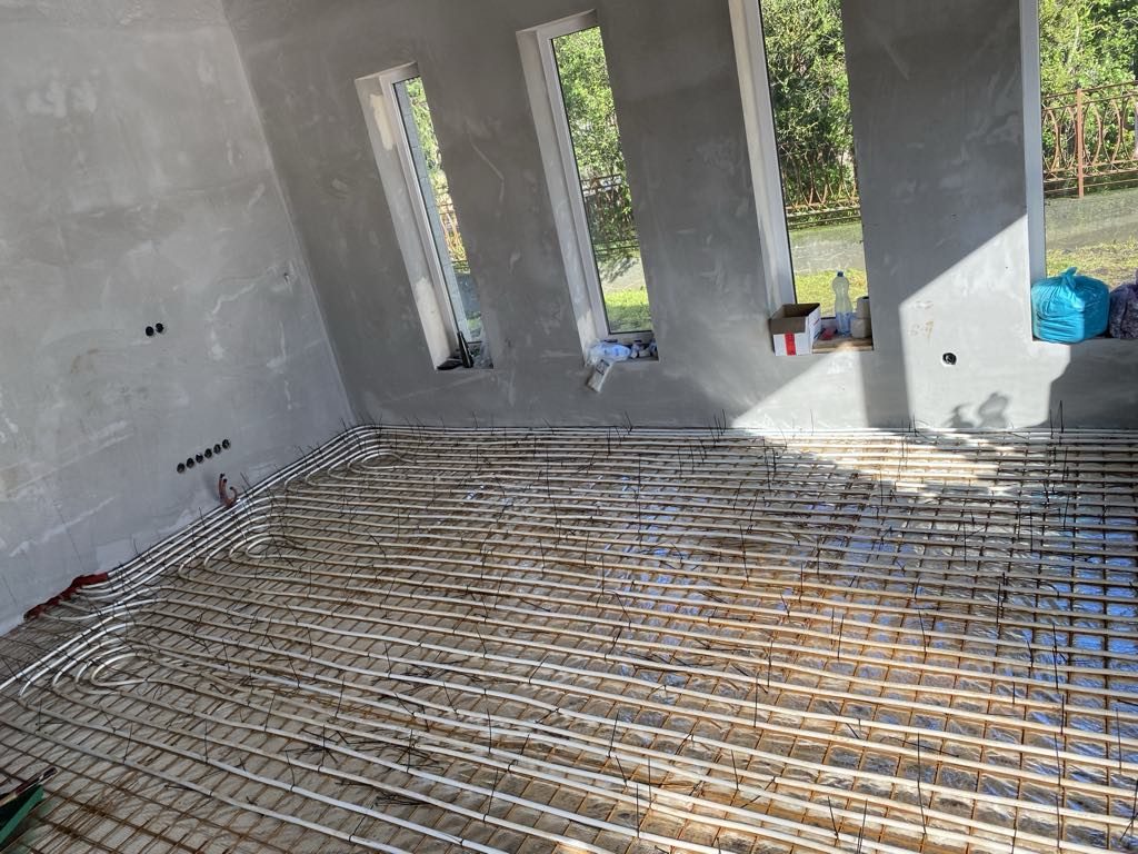 Padlófűtés csövei hőtükrös fólián és betonacél hálón egy nagy, háromablakos térben